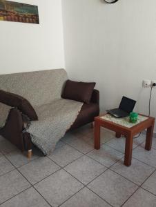 a living room with a couch and a table with a laptop at My Sisters House in Agios Nikolaos