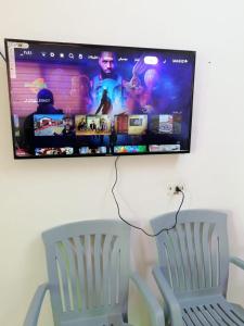 a flat screen tv hanging on a wall with a chair at Red rose apartment in Jerash