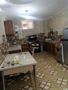 a large kitchen with a table and a refrigerator at Red rose apartment in Jerash
