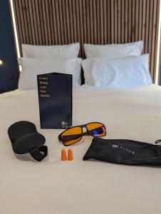 Una cama con un libro y gafas de sol. en OVYO Hôtel en Toulouse