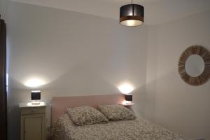 1 dormitorio con 1 cama con 2 lámparas y espejo en Gite de charme à la ferme 4 personnes, en Landrévarzec