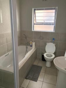 a bathroom with a toilet and a tub and a sink at Yanaz Place in Germiston