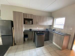 a kitchen with wooden cabinets and a refrigerator at Yanaz Place in Germiston