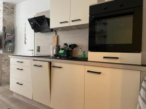 eine Küche mit weißen Schränken und einem Flachbild-TV in der Unterkunft Ferienwohnung Schloßberg Wohnung 2 in Eisenach