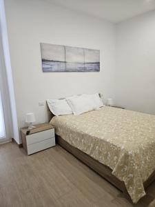 Habitación blanca con cama y mesita de noche en Santalucia Suite, en Modugno