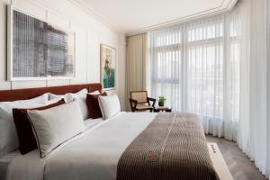 a bedroom with a large white bed and windows at The George Tel Aviv in Tel Aviv