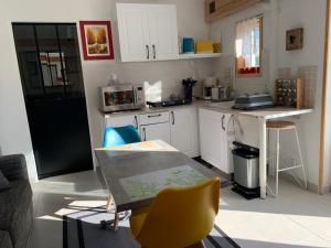 a kitchen with white cabinets and a table and chairs at T2 au calme montagne et lac in La Bâtie-Vieille +14 photos