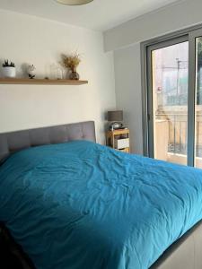 a blue bed in a bedroom with a window at Beau 2 pièces,Terrasse, Parking Menton Centre in Menton