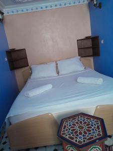 a bed with two pillows and a table on it at Casa Lotfi 1 in Chefchaouene