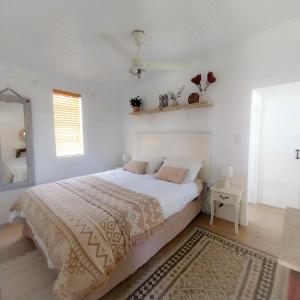 a white bedroom with a large bed and a mirror at The Little Gem in Montagu