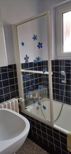 Łazienka z wanną i prysznicem wyłożona jest niebieskimi kafelkami. w obiekcie La maison de Tania w mieście Neuve-Église