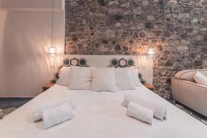 a bedroom with a large white bed with a stone wall at Médousa Bistrot & Suites in Taormina