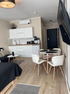 a living room with a table and chairs and a kitchen at Apartament Słoneczna Głębina - A 202 z klimatyzacją - Solny Resort in Kołobrzeg