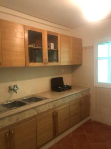 d'une cuisine avec des placards en bois, un évier et une fenêtre. dans l'établissement Pure immobilier, à Aït Saïd