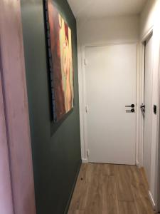 un pasillo con una puerta blanca y una pintura en la pared en Adorable Appartement de 60 m2 avec terrasse privée de 100m2 -lumineux - calme et verdure à 10 min de la mer, en Cagnes-sur-Mer