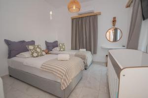 a hotel room with two beds and a mirror at Nèsoi Villas Naxos in Naxos Chora