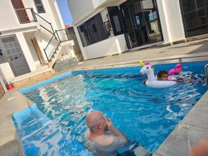 a man and a child in a swimming pool at Muguet by Ibiscot development in Kampala