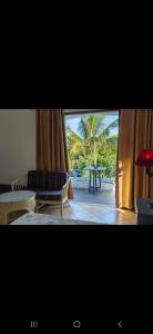 a living room with a couch and a table and a palm tree at Tam Studio in La Gaulette