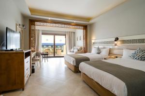 a hotel room with two beds and a flat screen tv at Sunrise Arabian Beach Resort in Sharm El Sheikh