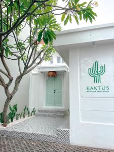 勒吉安的住宿－Kaktus Boutique Apartments Bali - ADULTS RETREAT，白色的建筑,有绿门和一棵树