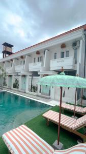 un hôtel avec une piscine et un parasol à côté dans l'établissement Kaktus Boutique Apartments Bali - ADULTS RETREAT, à Legian