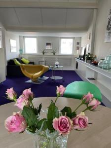 um vaso com rosas cor-de-rosa numa mesa num quarto em PetitGrandeur em Maastricht