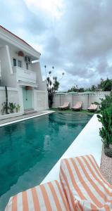勒吉安的住宿－Kaktus Boutique Apartments Bali - ADULTS RETREAT，一个带躺椅的游泳池以及一座房子