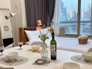 Seoul-lo Apartment في سول: زجاجة من النبيذ و مزهرية مع الزهور على الطاولة