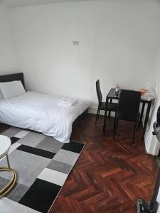 a room with a bed and a table and chairs at Nice and Cosy Studio Flat in Carshalton