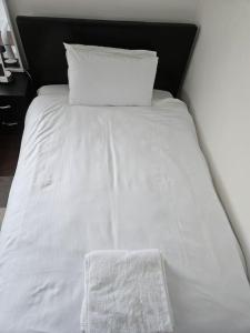a white bed with two pillows on top of it at Nice and Cosy Studio Flat in Carshalton
