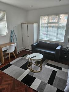 a living room with a black couch and a table at Nice and Cosy Studio Flat in Carshalton