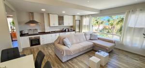 ein Wohnzimmer mit Couch und Küche in der Unterkunft Homes of Spain, Apartamentos Paraíso, Ed Palmerston, Atico O, Suite con Piscina Privada en solárium, vistas al mar, a 50 m de la playa, WIFI in Playas de Vera