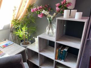 a book shelf with a vase of flowers and books at Best-Preis Ferienwohnung mit Netflix, Self-Check-In, eBike Ladestation im Fahrradraum, WLAN - direkt am Elberadweg im Herzen von Wittenberge in Wittenberge
