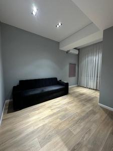 een zwarte bank in een kamer met een houten vloer bij Apartment 5 in Doesjanbe