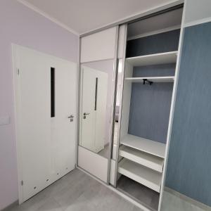 a walk in closet with white cabinets and a mirror at PasteLove Studio Apartament Pastelowe blisko Suntago Deepspot Mszczonów in Mszczonów