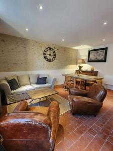 ein Wohnzimmer mit Ledermöbeln und einer Uhr an der Wand in der Unterkunft Le Nid'Ainay Maison de Village entièrement rénovée in Ainay-le-Vieil