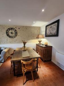 ein Esszimmer mit einem Tisch und einer Uhr an der Wand in der Unterkunft Le Nid'Ainay Maison de Village entièrement rénovée in Ainay-le-Vieil