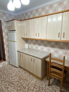 a kitchen with white cabinets and a table and a refrigerator at Alojamiento Rural VivoBosque in El Bosque