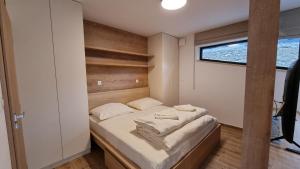 a small bedroom with a bed with white sheets at Chalets Hrabovo in Ružomberok