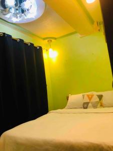 een slaapkamer met een wit bed en een groene muur bij Casa De Familia Staycation in Manilla