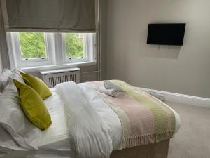 Central Park Hotel في لندن: سرير أبيض في غرفة نوم بها نافذتين