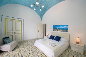 ein Schlafzimmer mit einem großen weißen Bett mit blauen Kissen in der Unterkunft AMORE RENTALS - Casa Barbera A in Positano