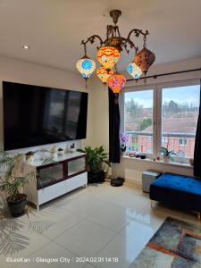 uma sala de estar com uma televisão de ecrã plano e lustres em La Casita, Your Home Away from Home - Free Parking em Glasgow