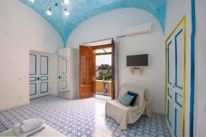 Zimmer mit einer Tür, einem Stuhl und einem TV in der Unterkunft AMORE RENTALS - Casa Barbera A in Positano
