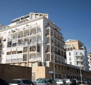 un gran edificio blanco con coches estacionados frente a él en Faro Sul Mare Luxury Apartment - Zona Fiera en Bari