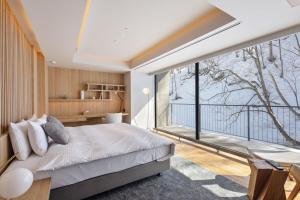 a bedroom with a bed and a large window at YAMAKEI Residences in Niseko