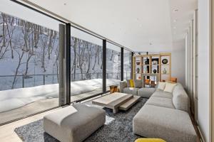 a living room with a couch and a large window at YAMAKEI Residences in Niseko