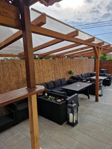 un patio con sofás y mesas bajo una pérgola de madera. en Nefelejcs Vendégház, en Gödöllő