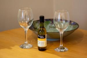 two wine glasses and a bottle of wine on a table at 2 wheelhouse apartments in Lochinver