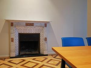Una chimenea en una habitación con 2 sillas azules y una mesa. en Appartamento Festival 8 en Muralto